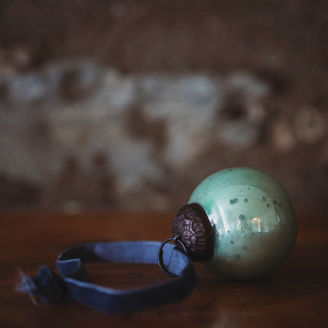 Green speckled ball with a brown knob on a wooden surface