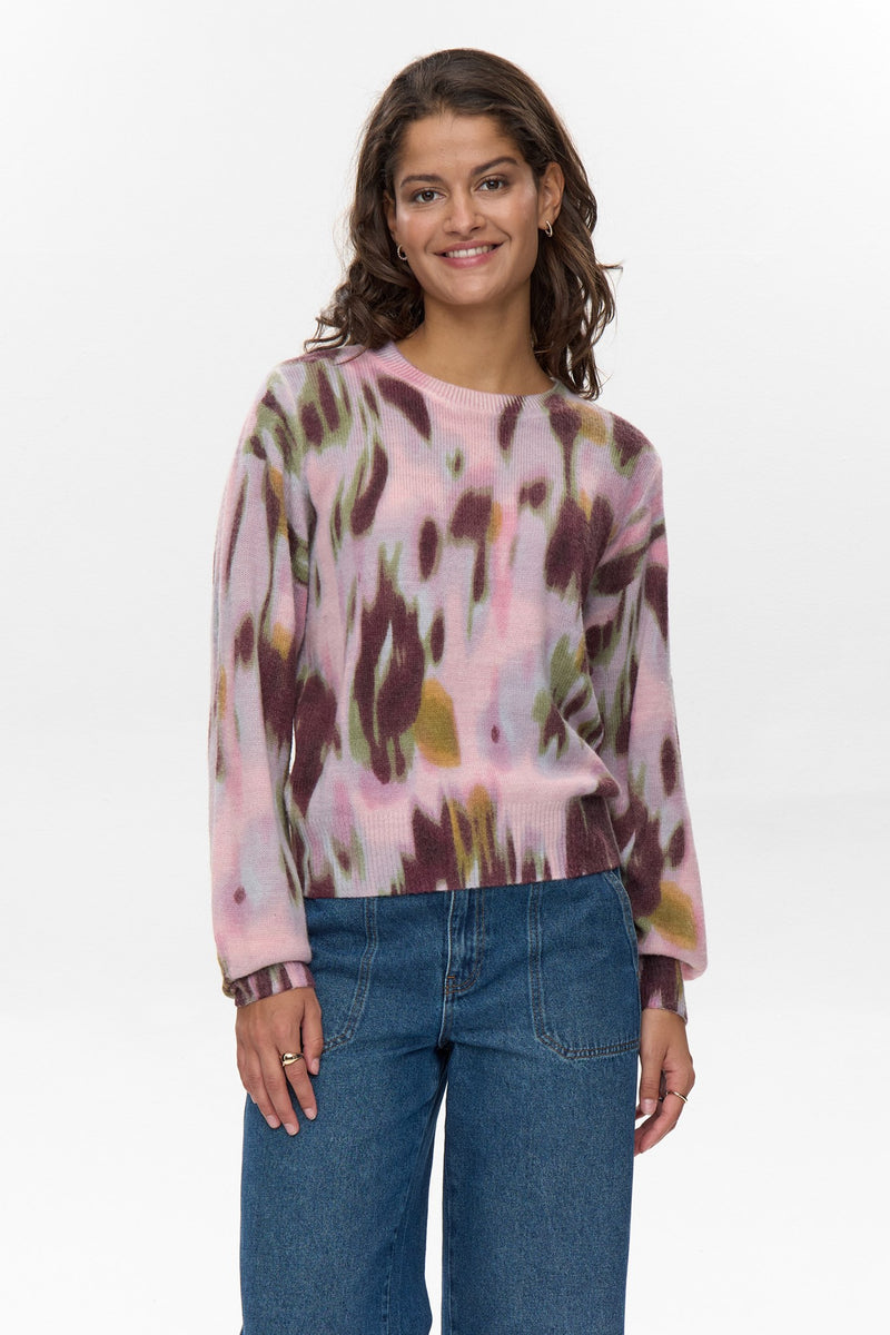 Woman wearing a colorful sweater and blue jeans on a white background