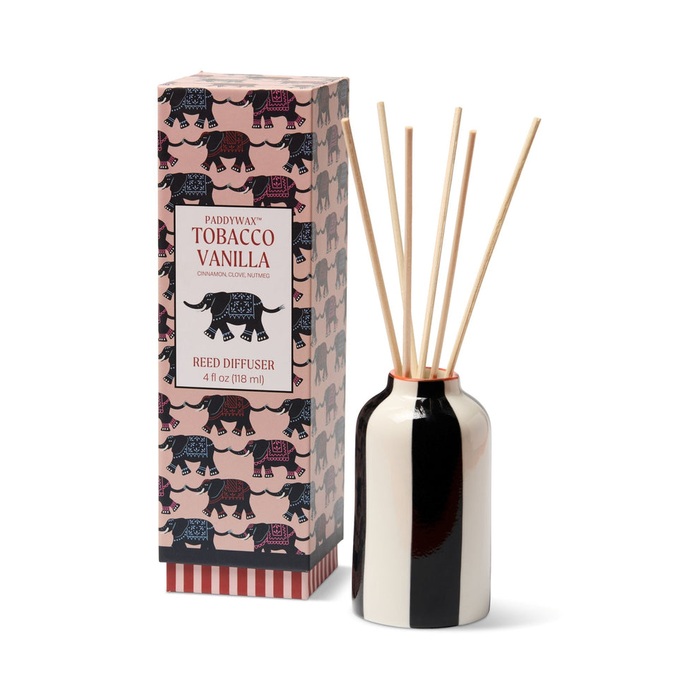 A reed diffuser set with a black and white ceramic bottle, four natural reed sticks, and its pink packaging box featuring a repeating elephant pattern and the text 'Pajamara Tobacco Vanilla'.
