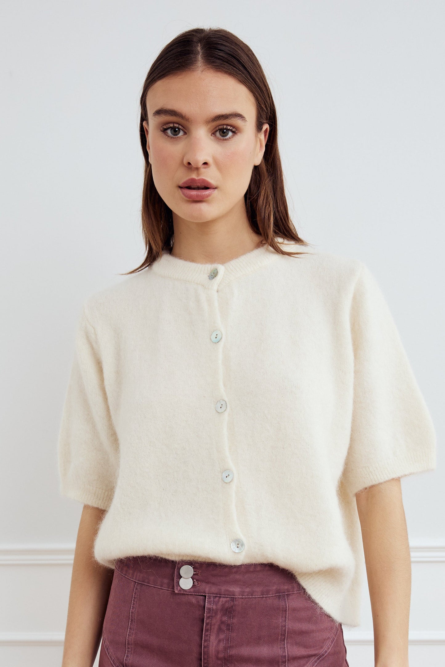 Noella Kae SS Knit Cardigan in Oyster. Woman wearing a cream-colored cardigan against a white background