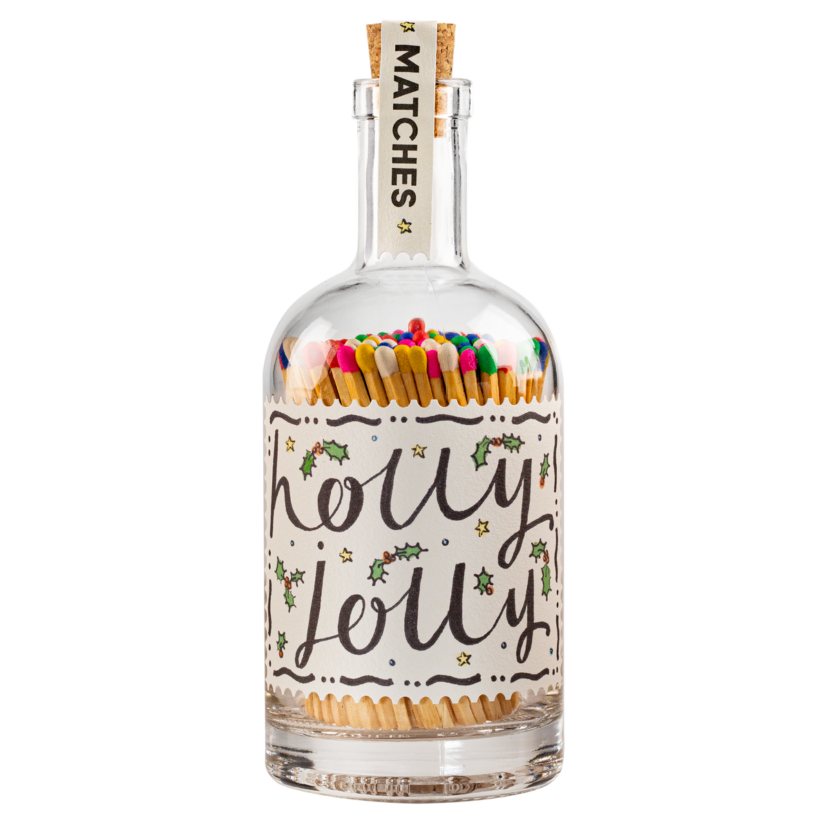 A clear glass bottle with a cork stopper, filled with colorful matches. The bottle has a white label with 'holly jolly' written in black script, decorated with small green holly leaves and gold stars.