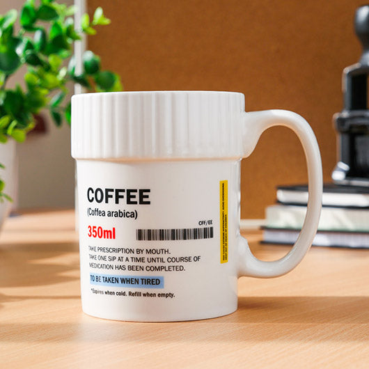 White mug labeled 'COFFEE' with a prescription-like design on a wooden surface.