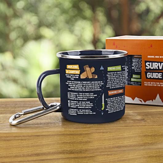 Navy blue mug with camping instructions on a wooden surface with a blurred natural background