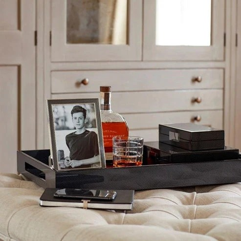 Addison Ross Carbon Fibre Lacquer Box with Silver 4x9 on a tray with a photo frame and bottle