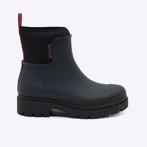 A single black rubber rain boot with a black elastic side panel and a red pull tab, shown from a side profile on a light gray background.