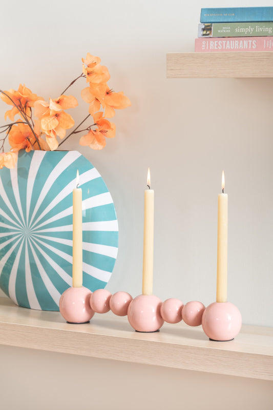 Present Time Candle Holder Bubbles Straight in Flamingo Pink next to a vase and below a wooden shelf with books on it