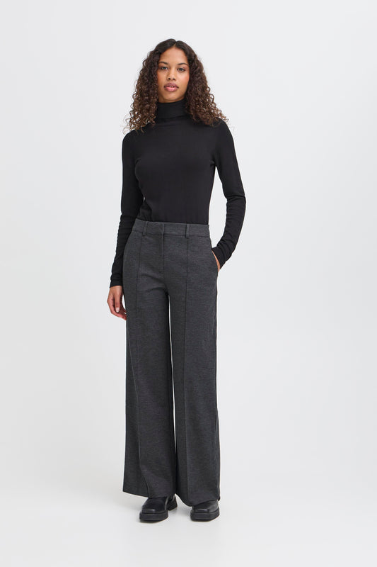 Woman wearing a black turtleneck and gray wide-leg pants on a white background