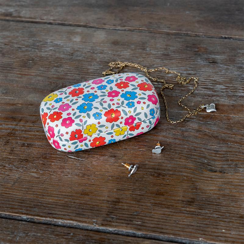 Floral-patterned jewelry case with necklace and earrings on a wooden surface