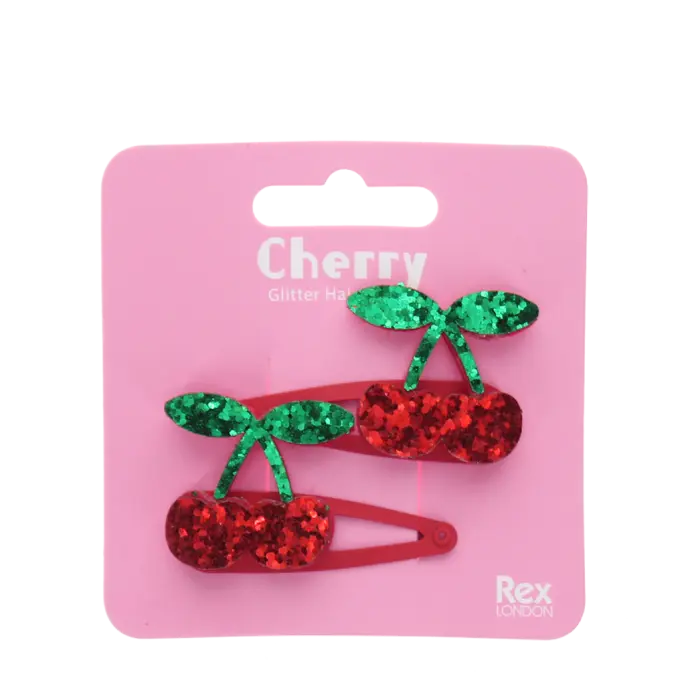 Packaged cherry-shaped hair clips with green and red glitter on a pink background, featuring the brand 'Rex London'.