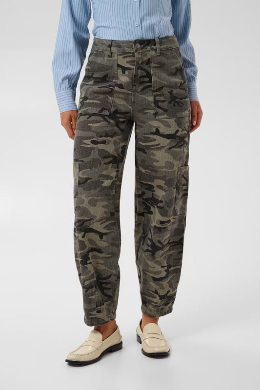 Kaffe Lilana Cargo Pants in Camo - A model wearing a pair of high-waisted, wide-leg camouflage trousers, styled with a light blue striped shirt and beige loafers, against a plain light gray studio background.