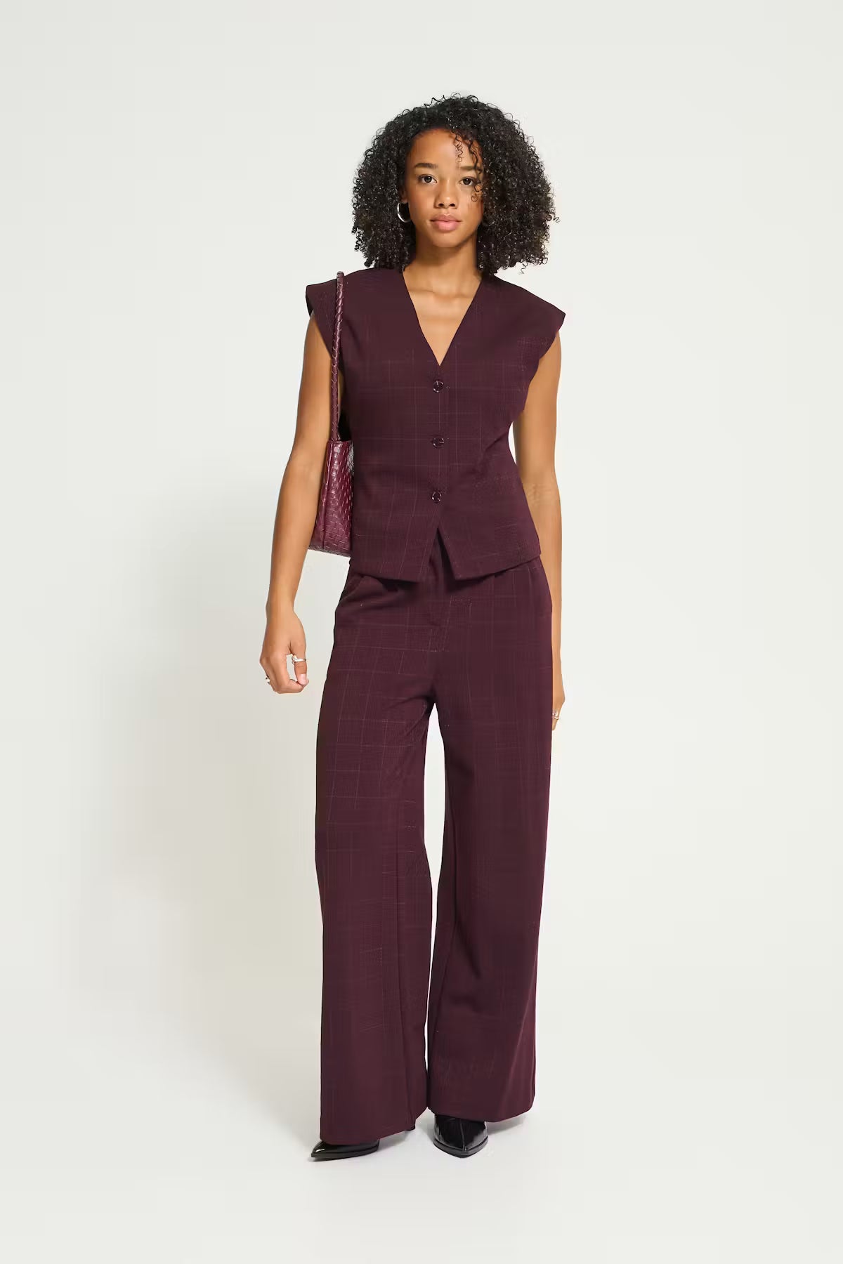 Ichi Kate Sparkelly Waistcoat in Fudge - A woman modelling a matching sleeveless button-front vest and wide-leg trousers set in a deep plum or burgundy tone, photographed against a clean light grey studio background.
