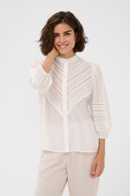 Woman wearing a white blouse with lace details on a white background