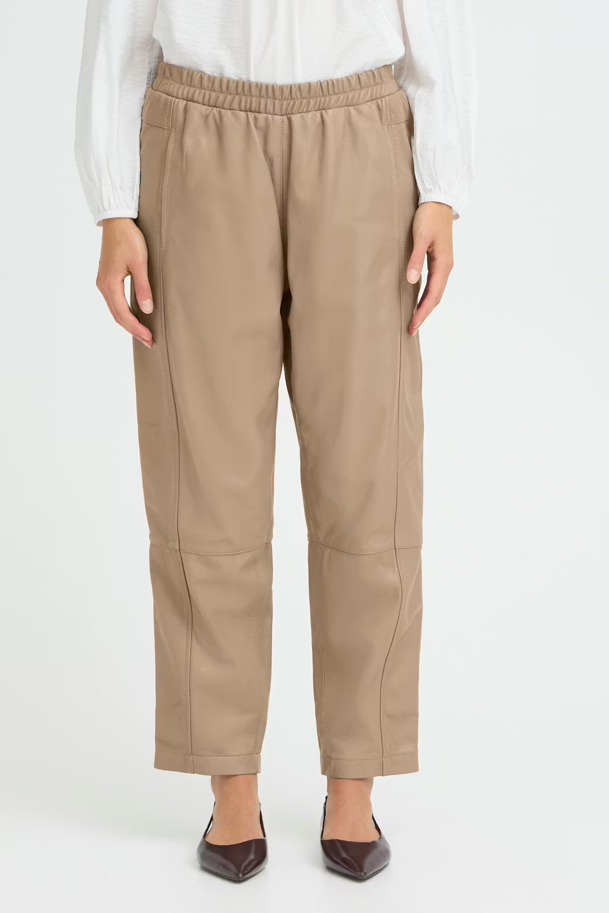 Beige pants worn by a person on a white background