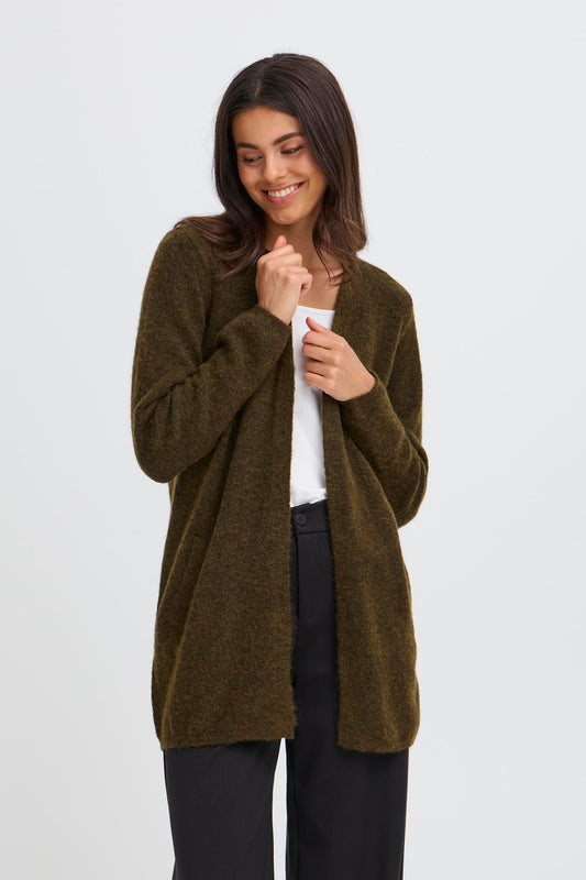 Woman wearing a dusty olive green cardigan over a white shirt and black pants on a white background
