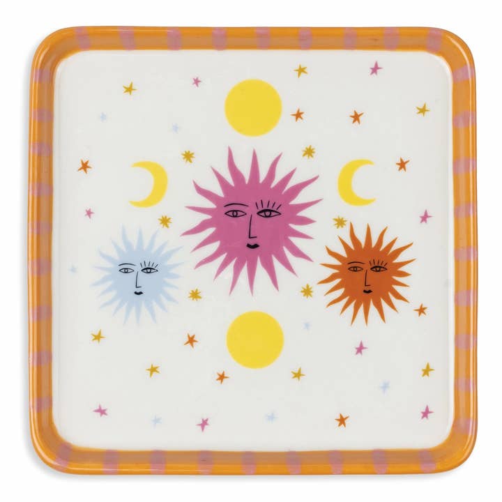 A square decorative plate with rounded corners, featuring a whimsical celestial design of three suns and crescent moons with faces on an off-white background, surrounded by small stars. The plate has a thick orange border with pink stripes.
