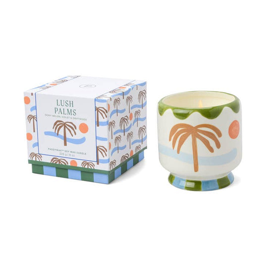Candle with palm tree design and matching box on a white background