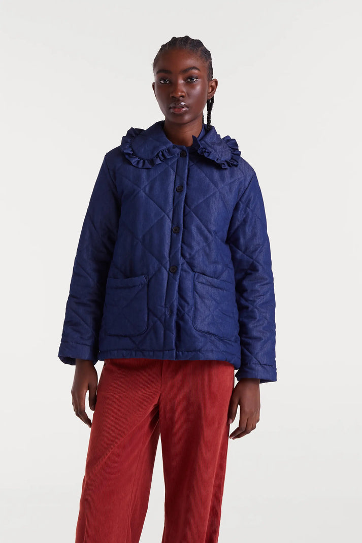 Person wearing a blue quilted jacket and red pants on a white background