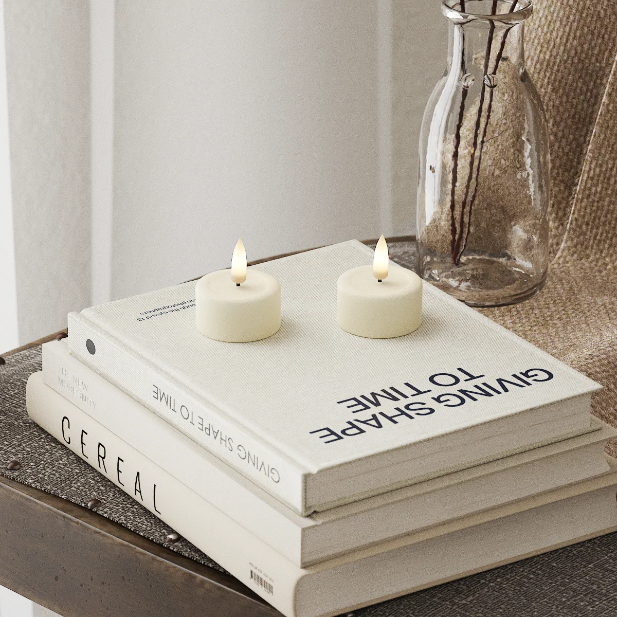 Stack of books with candles on top, placed on a textured surface with a neutral background.