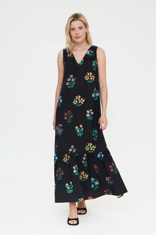 Woman wearing a black sleeveless dress with colorful floral pattern on a white background