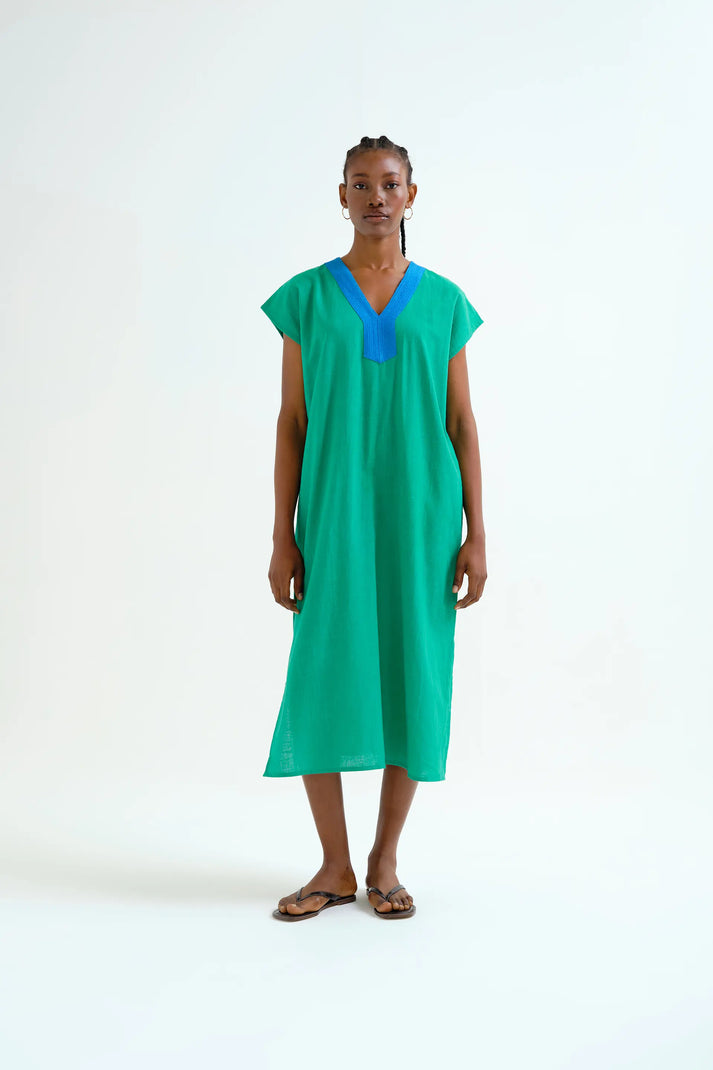 Woman wearing a green dress with a blue neckline on a white background
