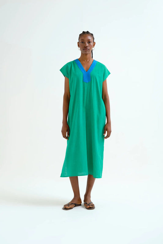 Woman wearing a green dress with a blue neckline on a white background