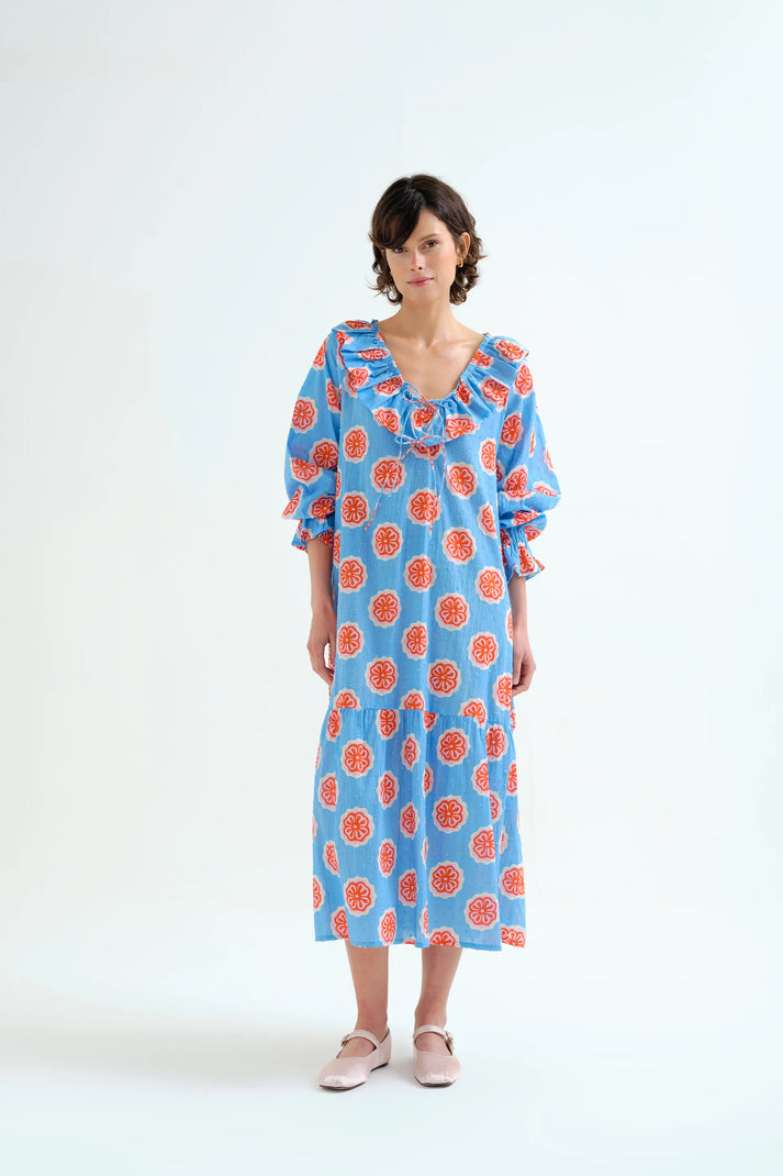Woman wearing a blue dress with red floral pattern on a white background