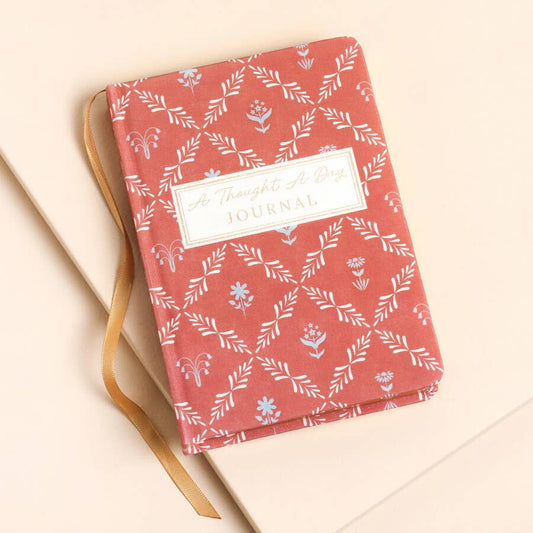 Red journal with floral pattern on a beige surface