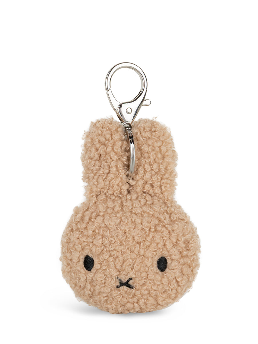 A beige teddy-bunny-shaped keychain with embroidered black eyes and mouth, attached to a silver metal key ring, shown on a plain white background.
