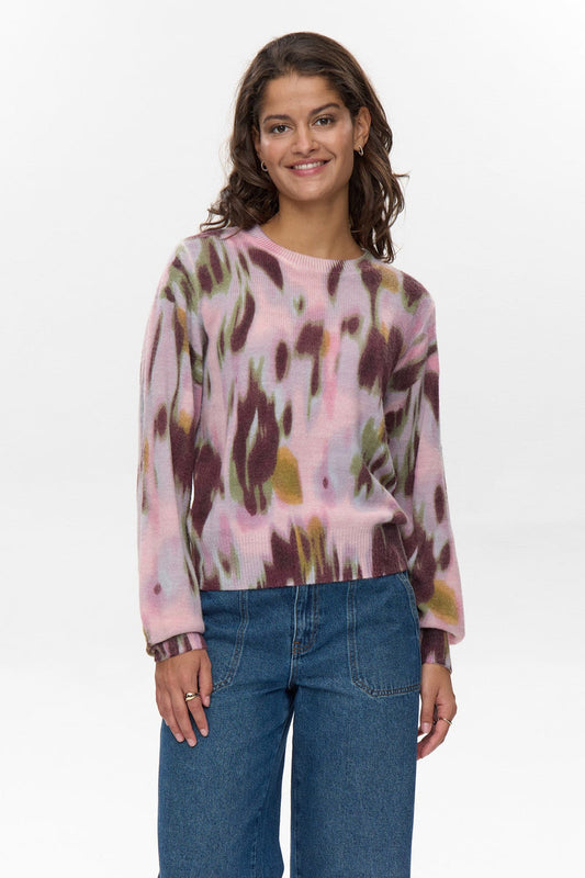 Woman wearing a colorful sweater and blue jeans on a white background