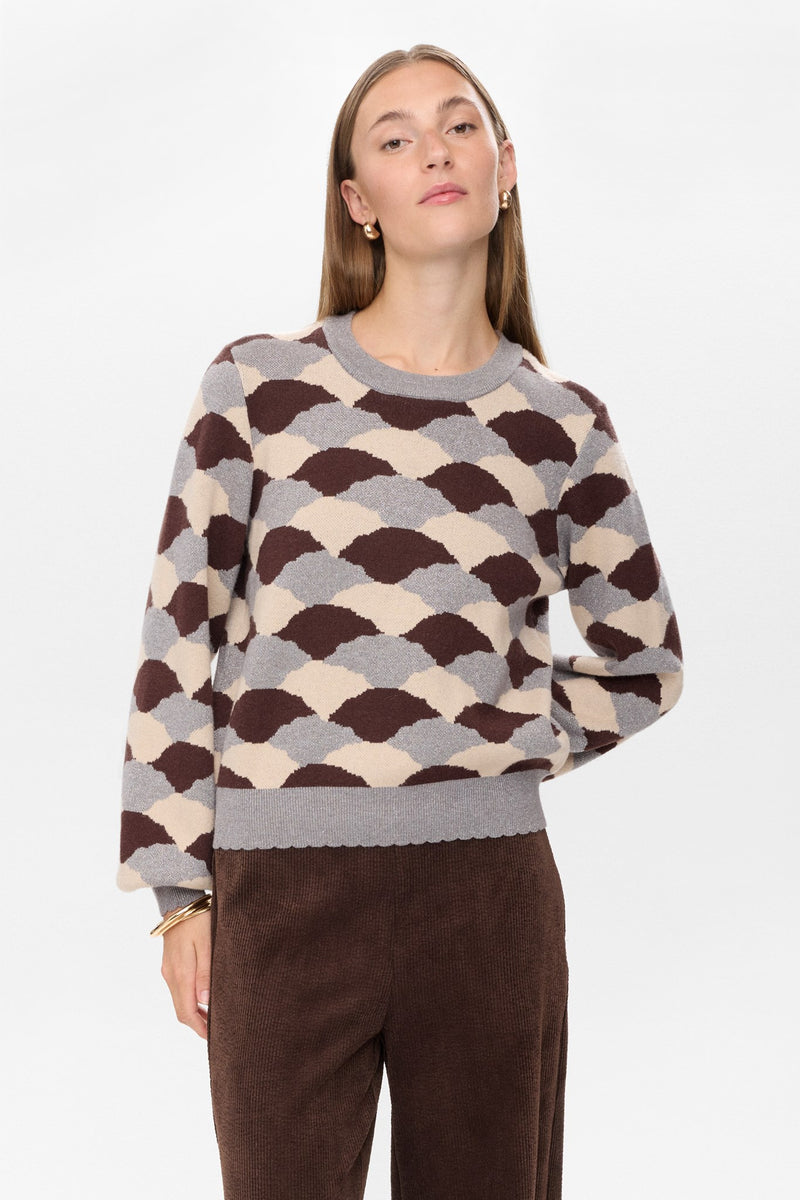 Woman wearing a patterned sweater with a plain background