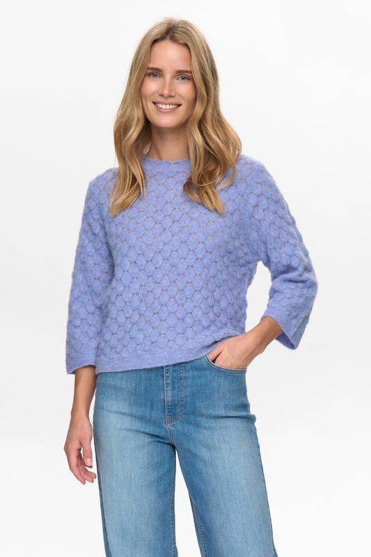 Woman wearing a light purple sweater and jeans on a white background
