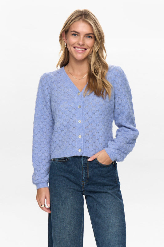 Woman wearing a blue cardigan and jeans on a white background