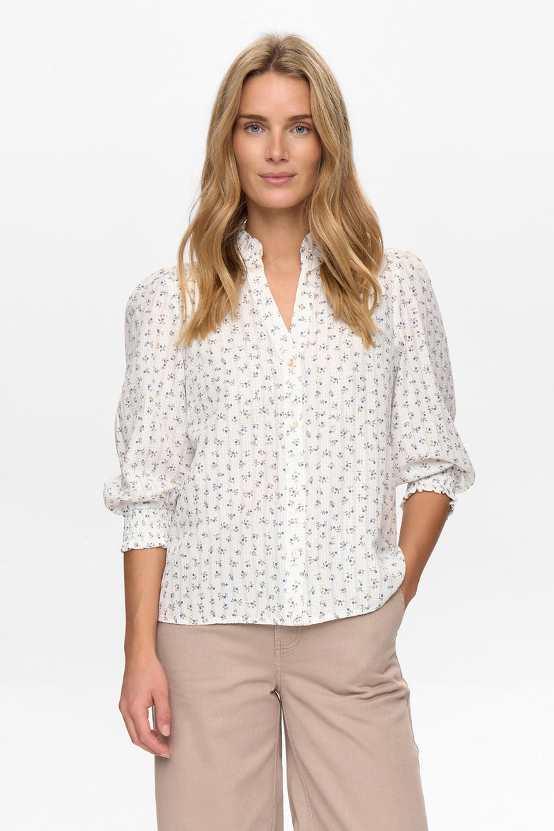 Woman wearing a white blouse with a subtle pattern on a white background