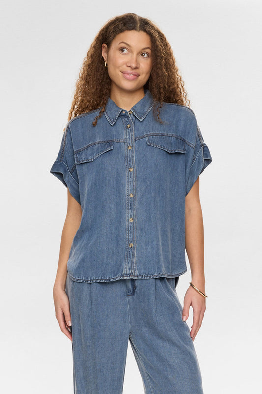 Woman wearing a denim shirt and pants on a white background