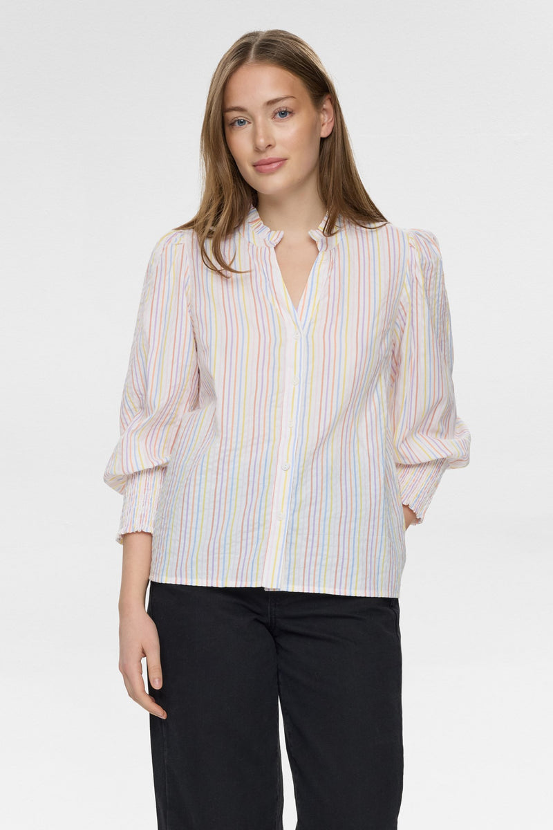 Woman wearing a striped blouse and black pants on a white background