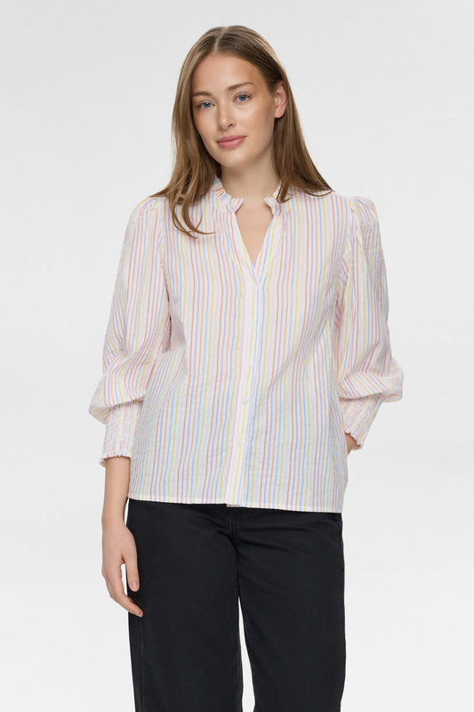 Woman wearing a striped blouse and black pants on a white background