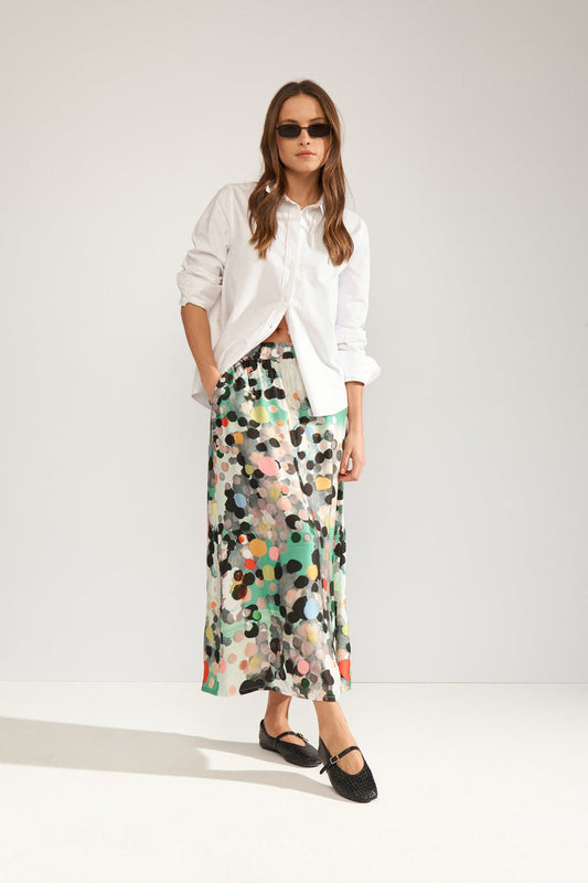 Woman wearing a white blouse and colorful patterned skirt on a white background