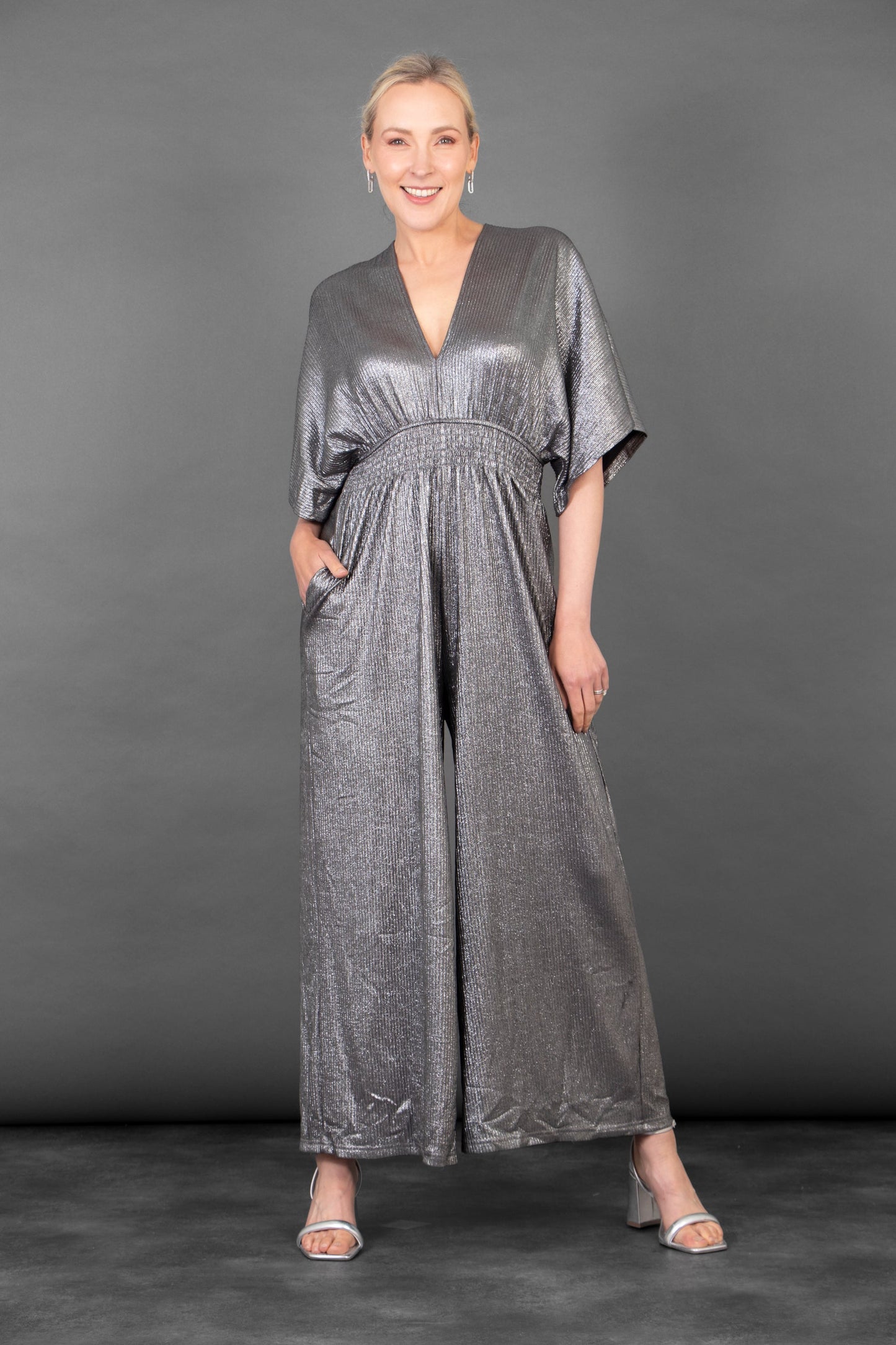 Woman wearing a silver jumpsuit against a gray background