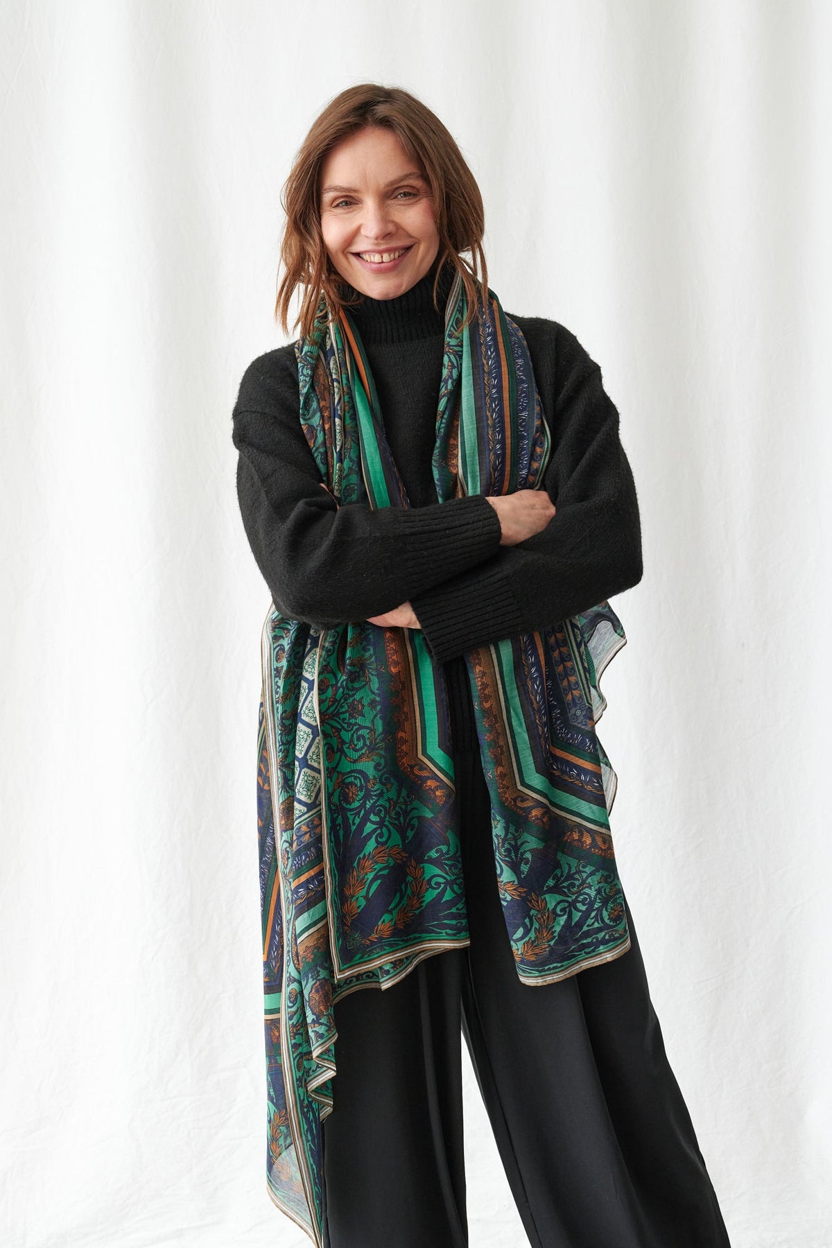 One Hundred Stars Amulet Emerald Scarf - Woman wearing a colourful scarf with a black sweater and pants on a white background