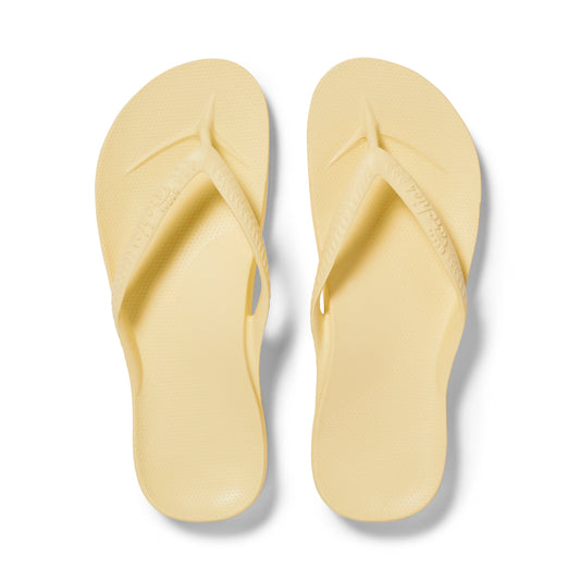 Pair of light yellow flip-flops on a white background