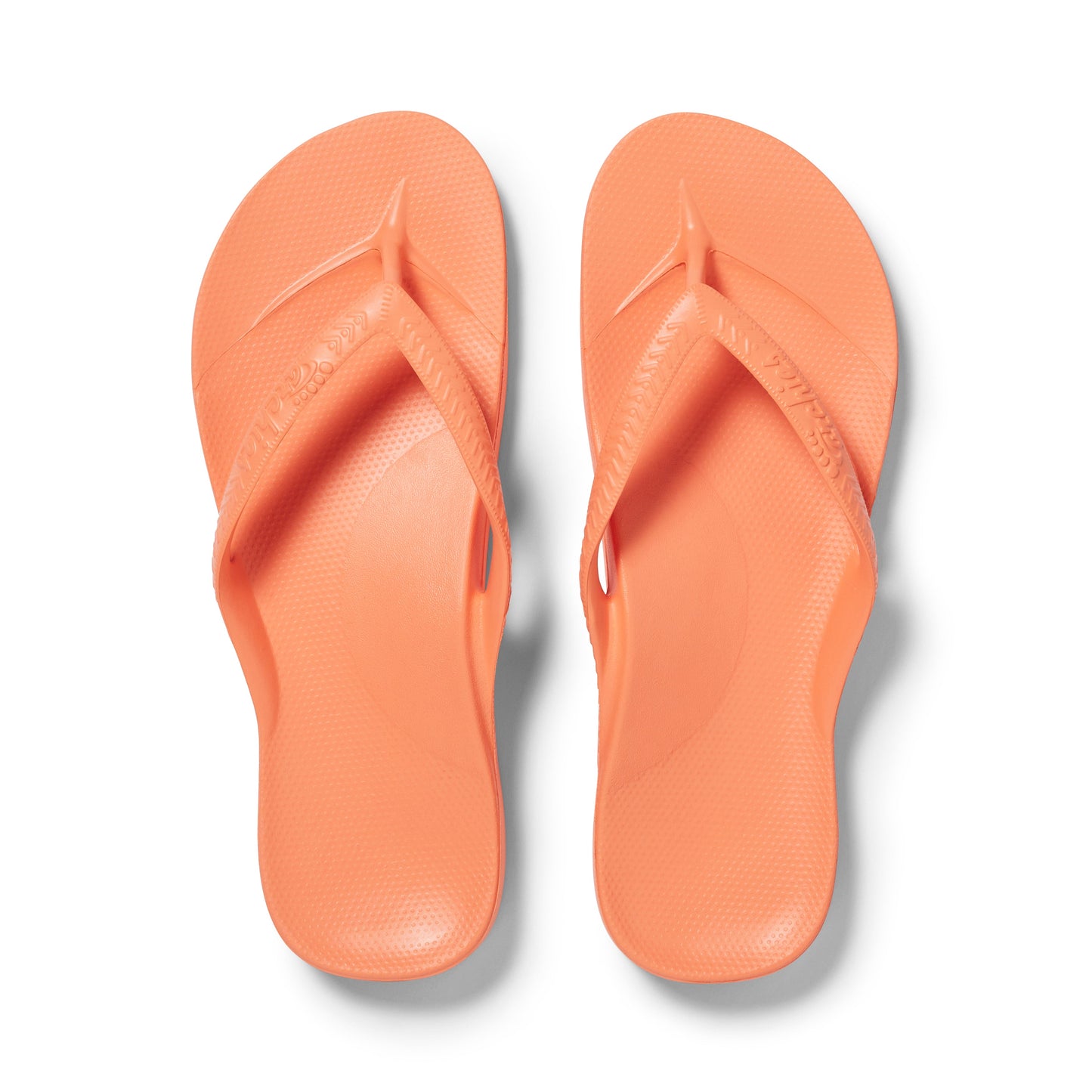 Pair of peach flip-flops on a white background
