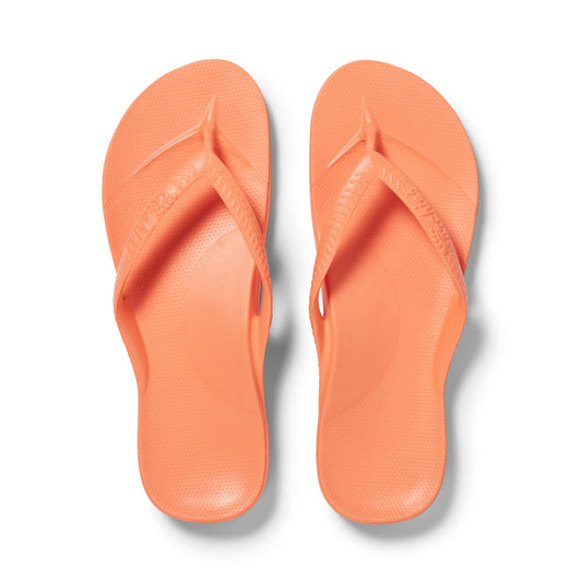 Pair of peach flip-flops on a white background