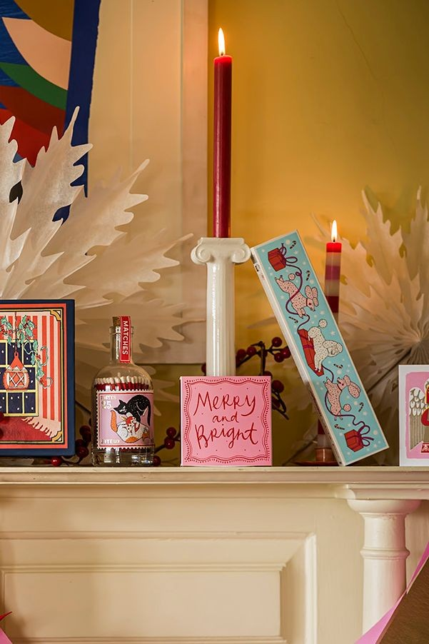 Decorative mantel with Archivist candles, matches, signs, and framed pictures on a fireplace.