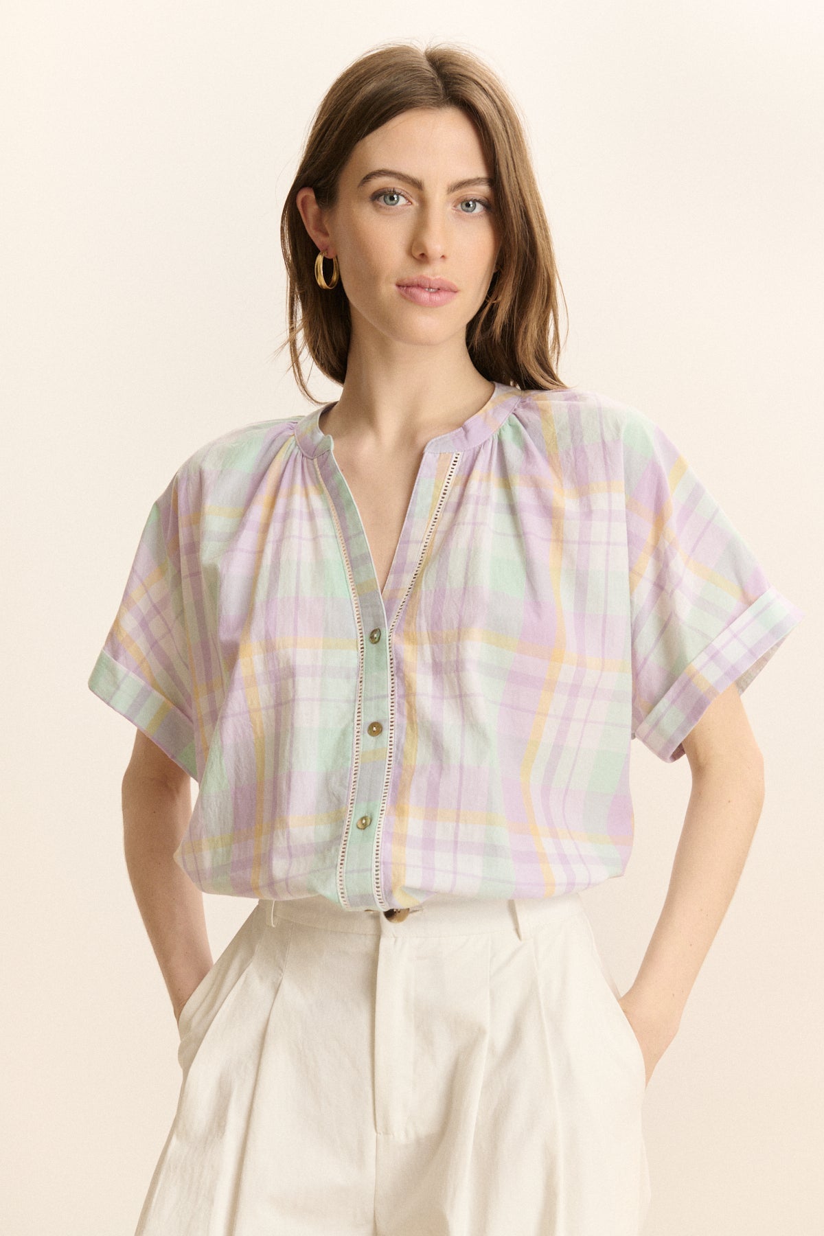 Woman wearing a pastel plaid shirt with a neutral background