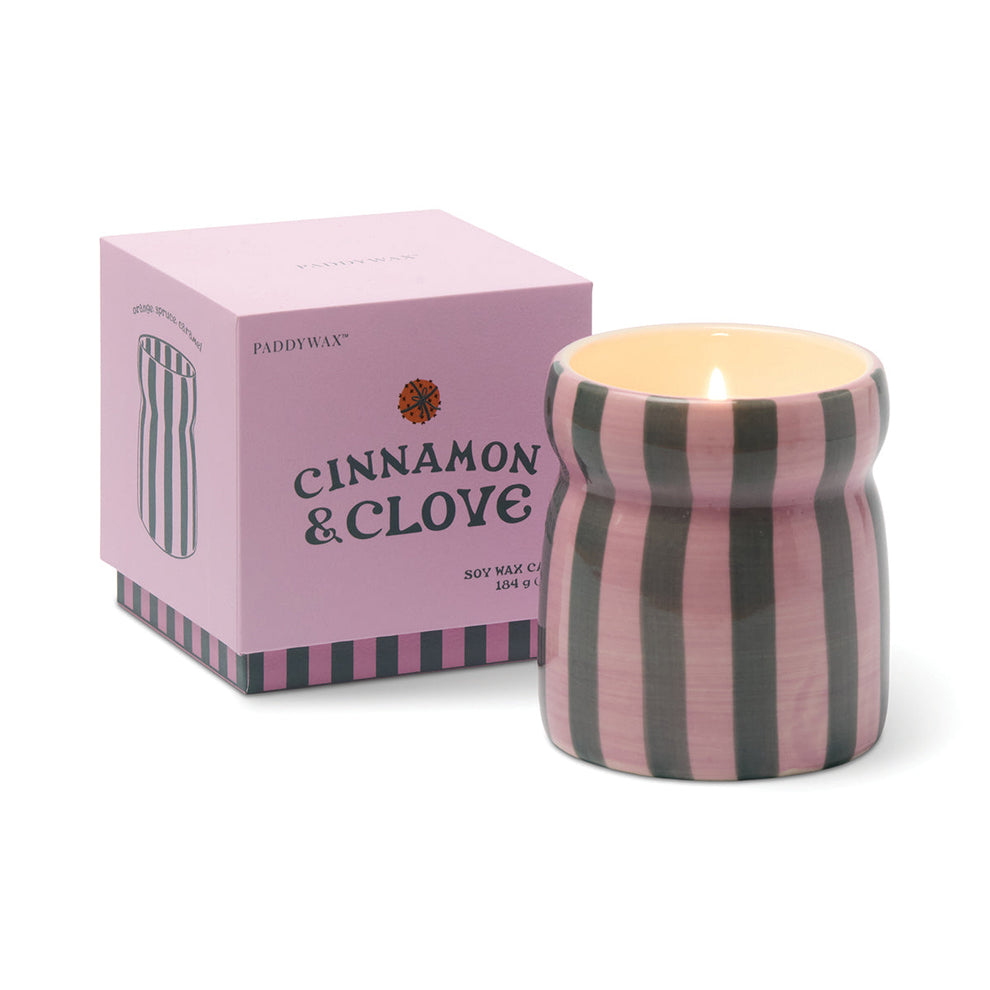 Striped candle with 'Cinnamon & Clove' packaging on a white background