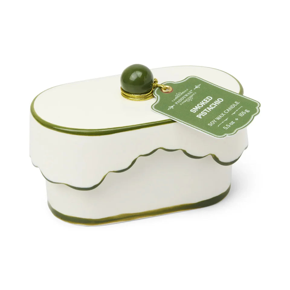 White candle shaped like a cake with green accents on a white background
