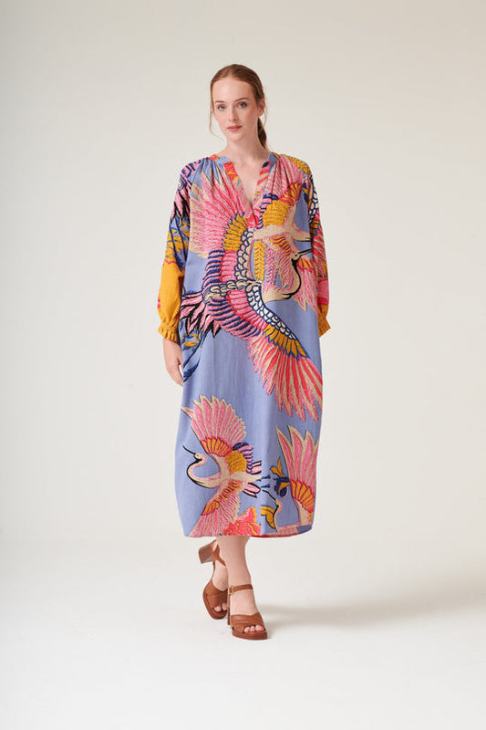 Woman wearing a colorful dress with bird patterns on a white background