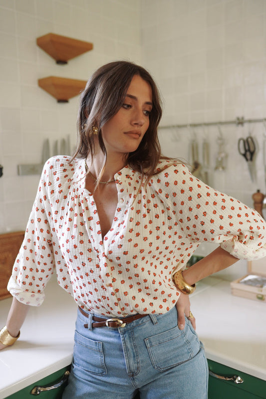 Woman in a kitchen wearing a polka dot blouse and high-waisted jeans.
