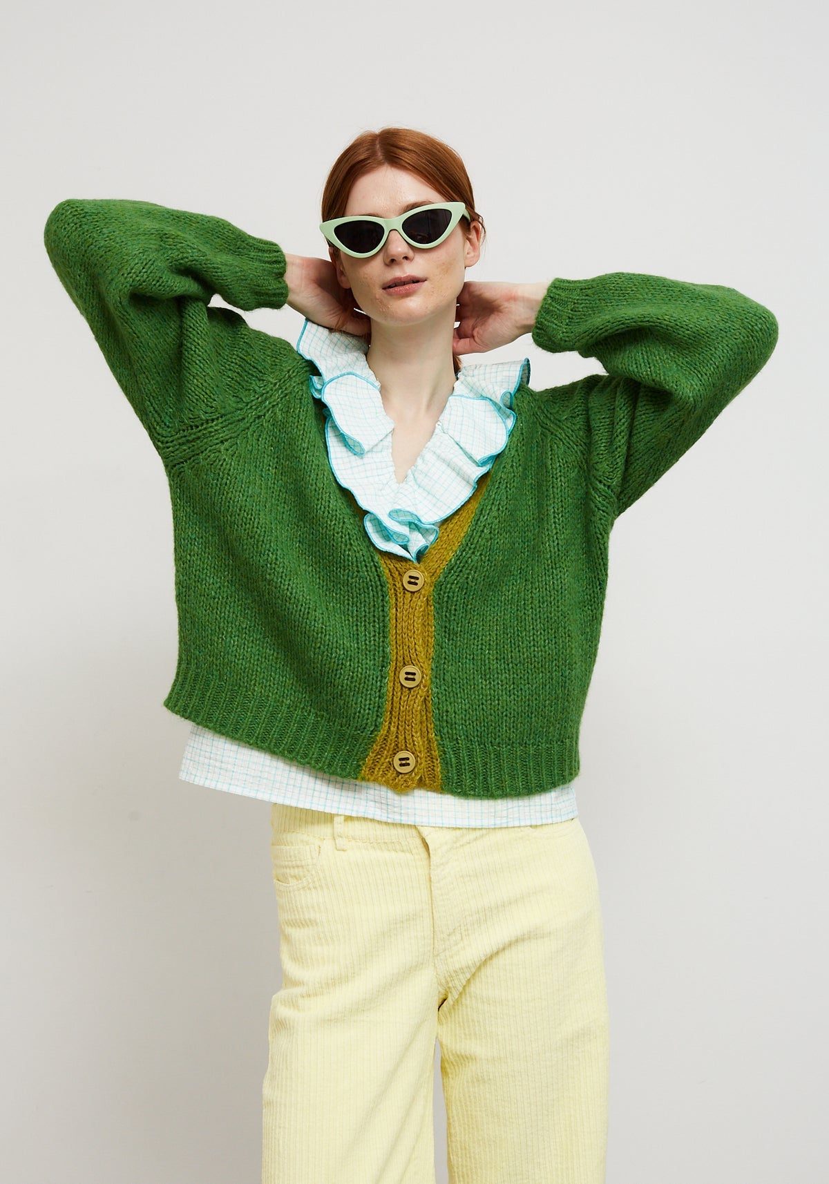 Dr Bloom Cocoon Green Cardigan. Person wearing a green cardigan with a white shirt and yellow pants on a plain background