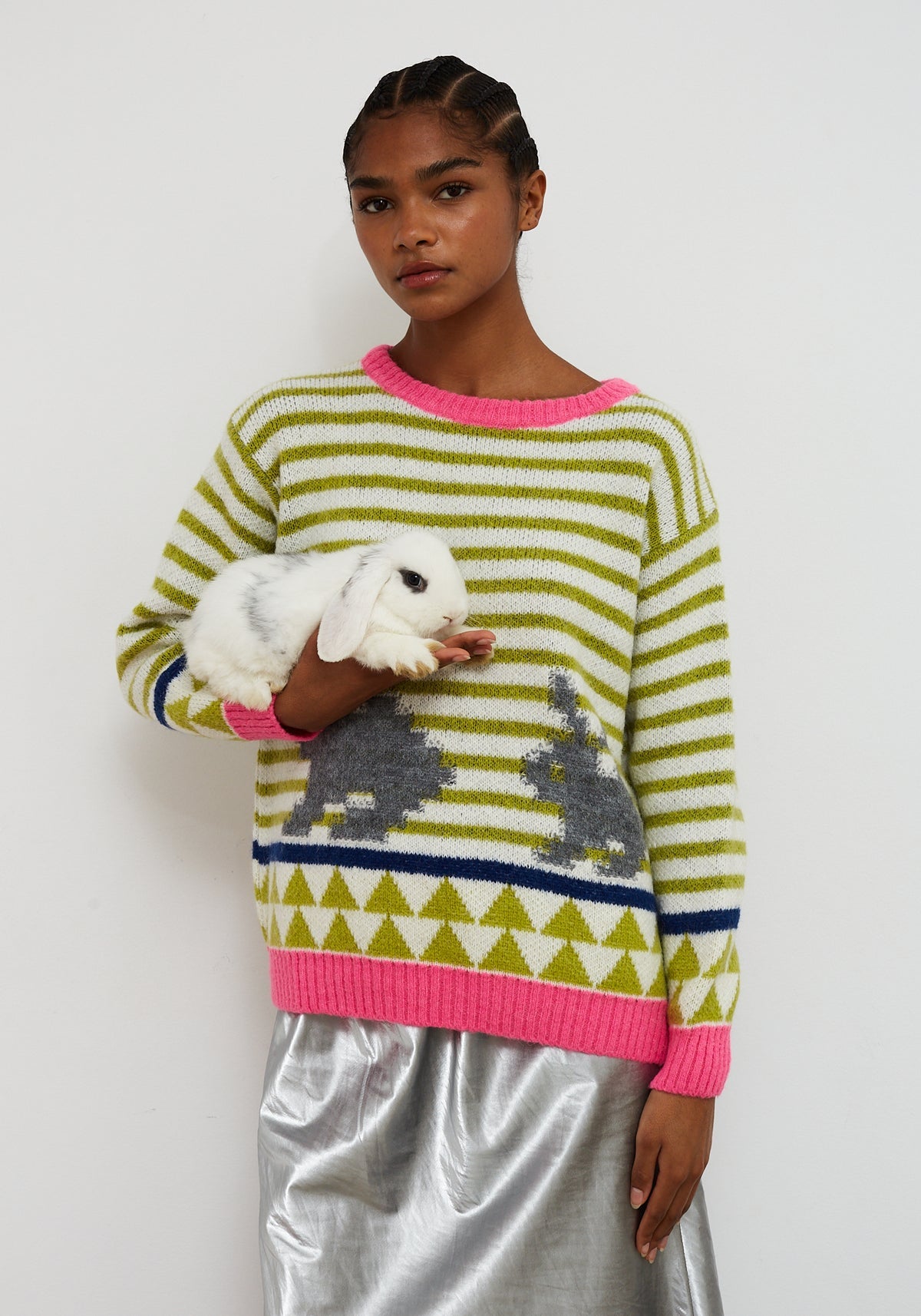 Dr Bloom Jersey Rabbit Green. Person wearing a colourful striped sweater with bunny designs, holding a small white rabbit.